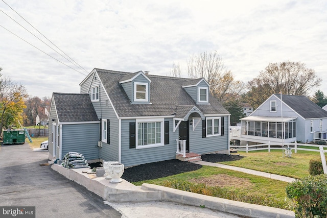 cape cod home featuring a front lawn