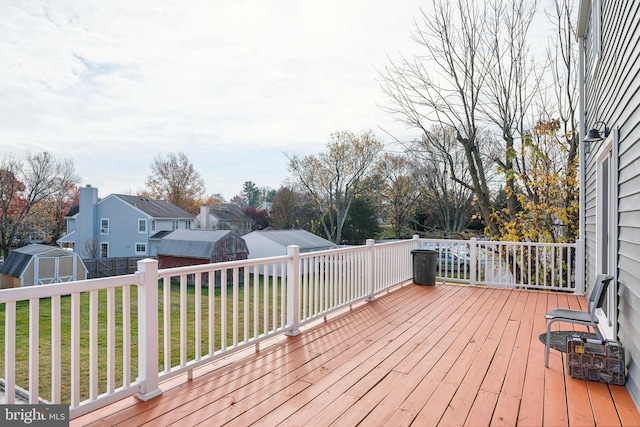 wooden deck with a lawn and a storage unit