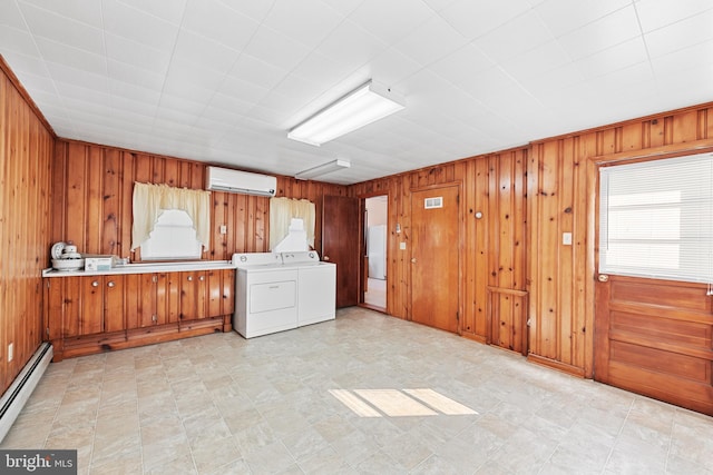 interior space featuring wood walls, baseboard heating, light tile floors, washer and dryer, and a wall mounted AC