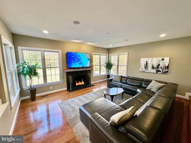 living room with a fireplace, recessed lighting, wood finished floors, and visible vents