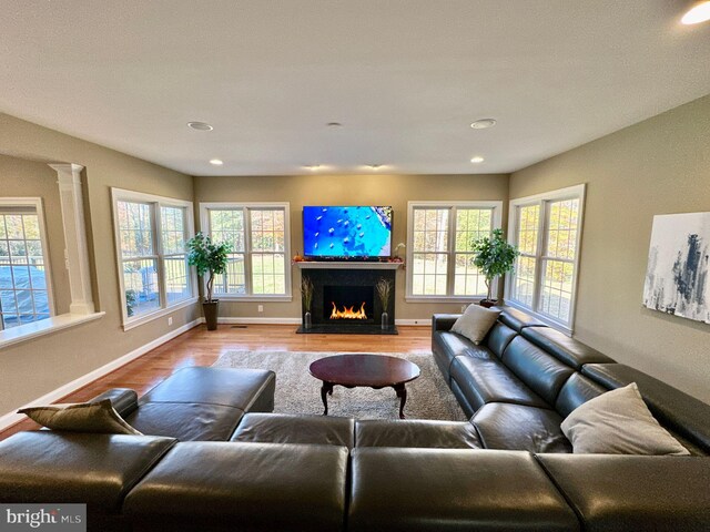 living room with recessed lighting, baseboards, a lit fireplace, and wood finished floors