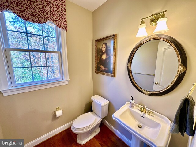 bathroom featuring wood finished floors, toilet, baseboards, and a sink