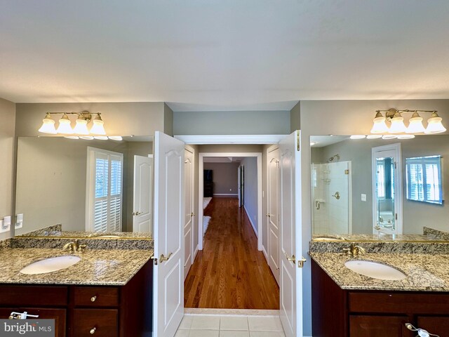 full bath with a sink, two vanities, and a stall shower