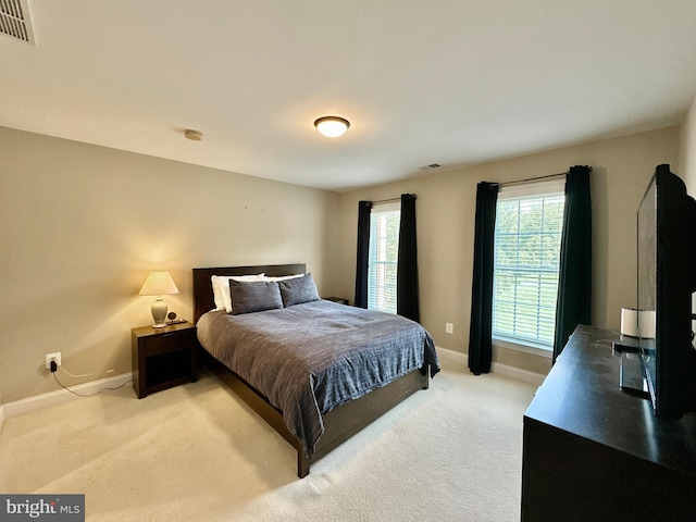 bedroom with light carpet, visible vents, and baseboards