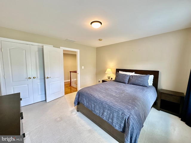 bedroom featuring visible vents, light colored carpet, and a closet