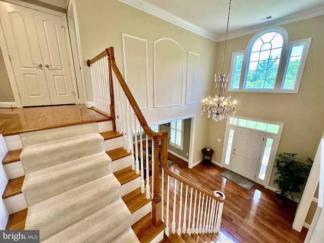 entryway featuring stairs, visible vents, wood finished floors, and crown molding