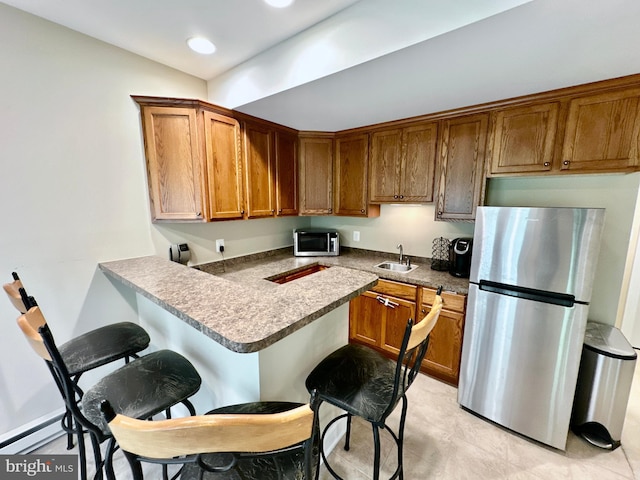 kitchen featuring a kitchen breakfast bar, brown cabinets, appliances with stainless steel finishes, and a sink