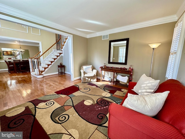 living room with visible vents, crown molding, stairway, wood finished floors, and a notable chandelier