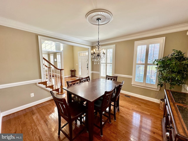 dining space with hardwood / wood-style floors, crown molding, baseboards, and visible vents