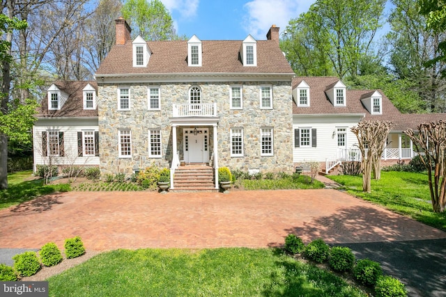 rear view of house with a balcony and a yard