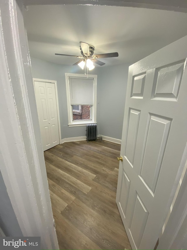 interior space featuring radiator heating unit, ceiling fan, and dark hardwood / wood-style floors