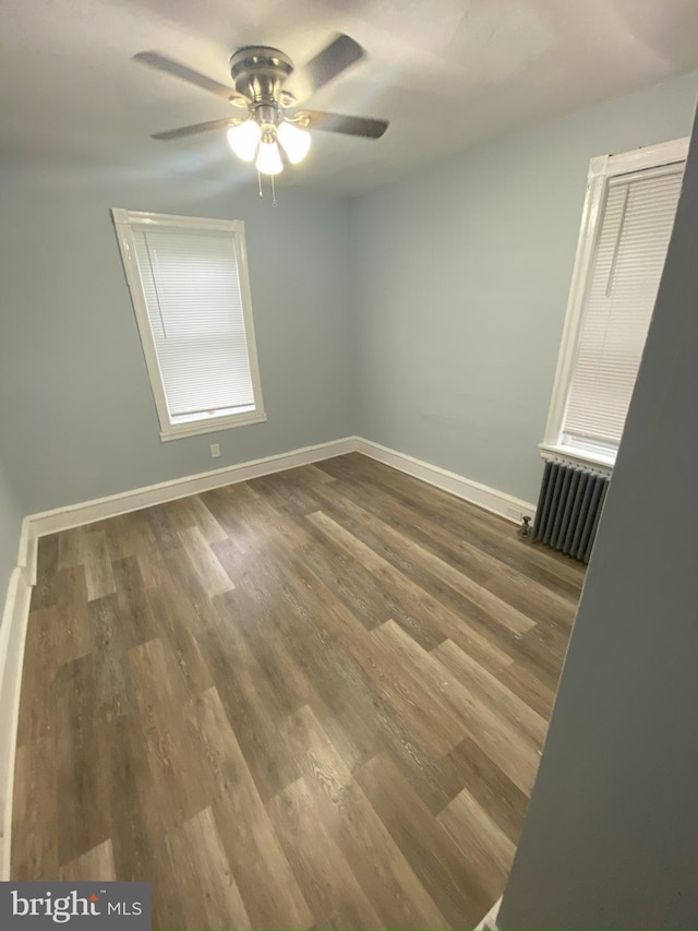 spare room with ceiling fan, radiator, and dark hardwood / wood-style flooring