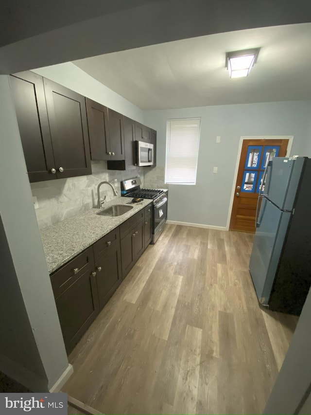 kitchen featuring tasteful backsplash, stainless steel appliances, dark brown cabinets, light hardwood / wood-style flooring, and light stone countertops