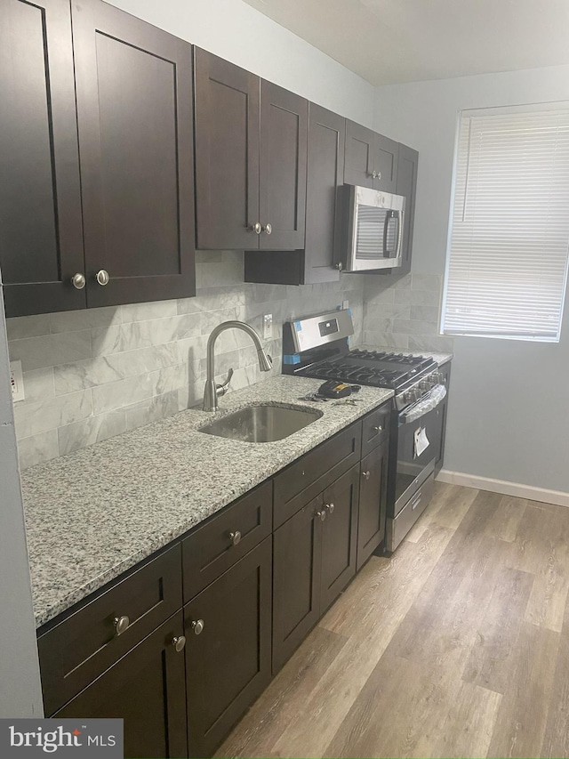 kitchen featuring light stone countertops, light hardwood / wood-style floors, appliances with stainless steel finishes, and sink