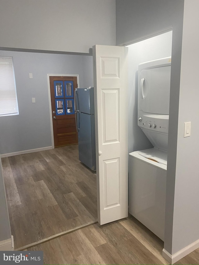 clothes washing area featuring dark hardwood / wood-style flooring and stacked washing maching and dryer