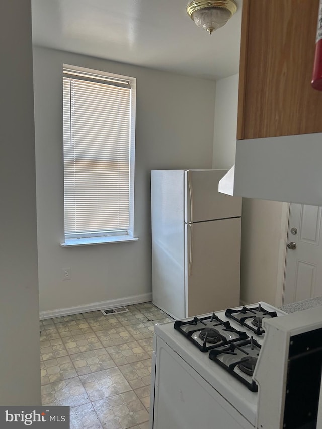 kitchen featuring white cabinets, light tile floors, stove, and white fridge