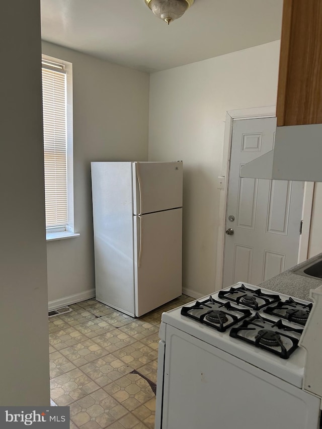 kitchen with white refrigerator, range, light tile floors, and white cabinets