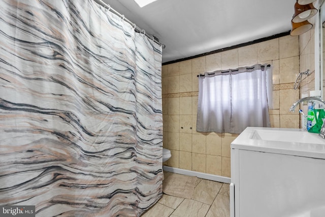 bathroom featuring tile walls, tile flooring, toilet, and vanity