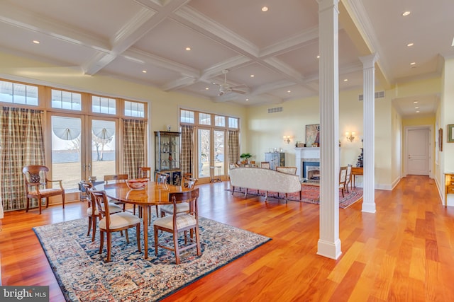 dining space featuring light wood-type flooring, beamed ceiling, and ornate columns