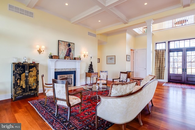 living room with coffered ceiling, hardwood / wood-style flooring, beamed ceiling, and ornate columns