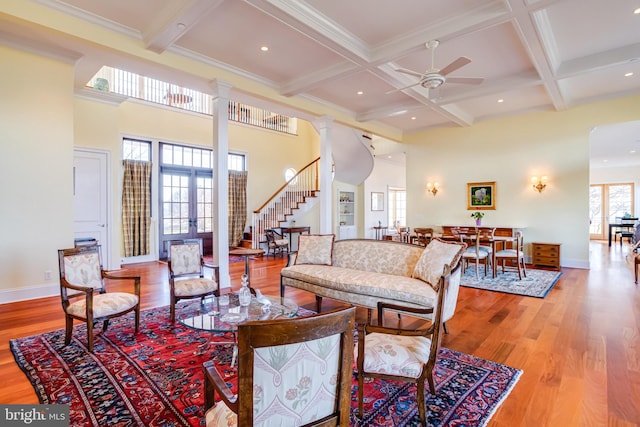 living room with ornate columns, beamed ceiling, coffered ceiling, ceiling fan, and light hardwood / wood-style floors