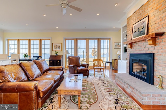 living room featuring french doors, a healthy amount of sunlight, ornamental molding, and a brick fireplace