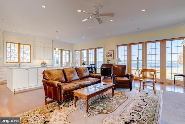 living room with ceiling fan, crown molding, a water view, light wood-type flooring, and french doors