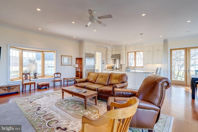 living room featuring ornamental molding, ceiling fan, and light hardwood / wood-style flooring