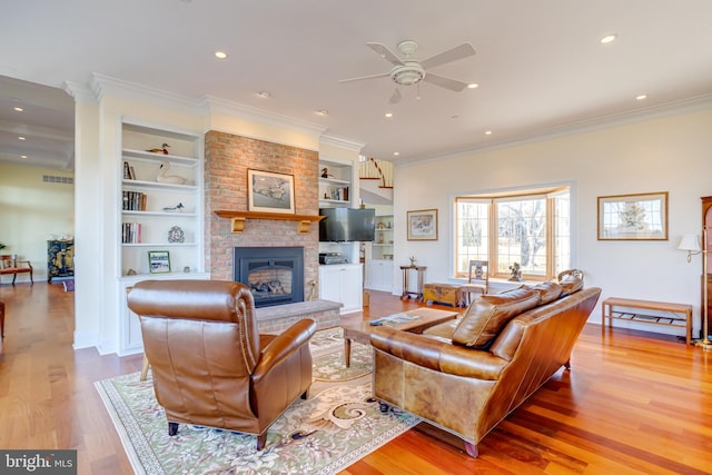 living room with light hardwood / wood-style flooring, a brick fireplace, ornamental molding, and built in features