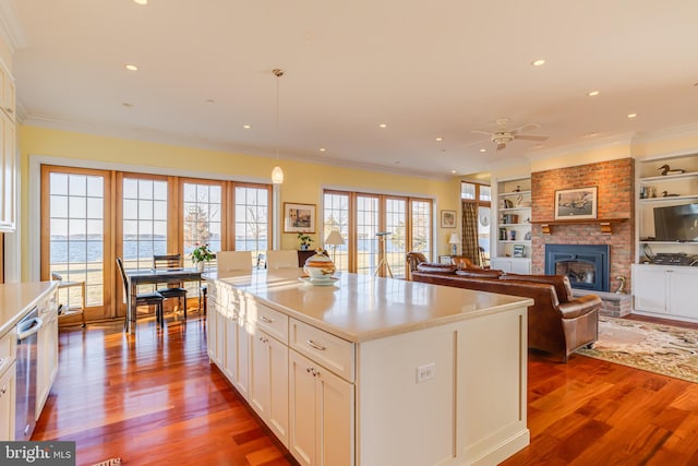 kitchen with pendant lighting, built in features, white cabinetry, a water view, and wood-type flooring