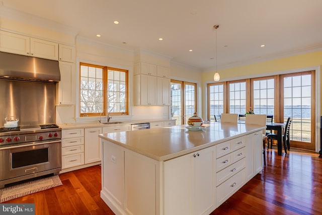 kitchen featuring a water view, hanging light fixtures, appliances with stainless steel finishes, a kitchen island, and white cabinets