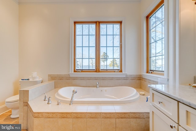 bathroom with tiled tub, vanity, and toilet