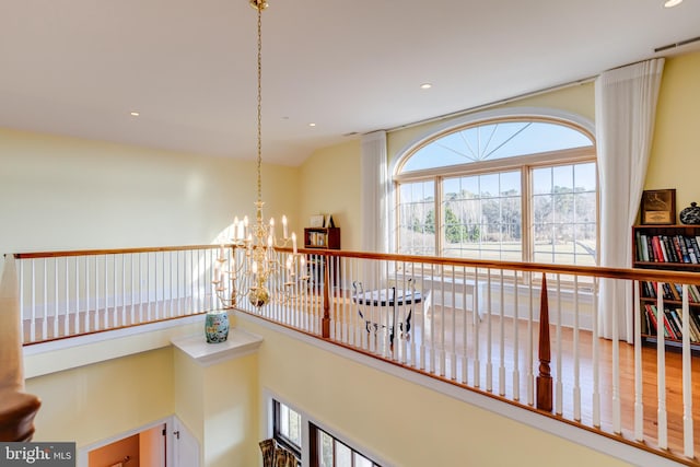 corridor featuring lofted ceiling and a chandelier