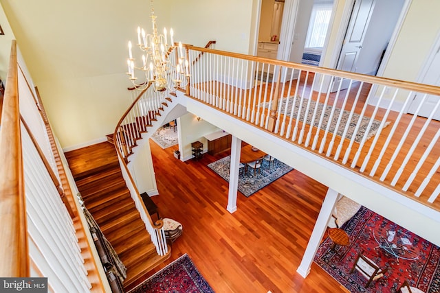 staircase featuring wood-type flooring and a chandelier