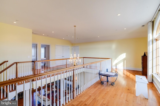 hallway featuring an inviting chandelier and light hardwood / wood-style floors