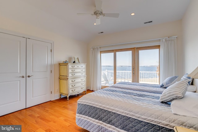 bedroom with a water view, light wood-type flooring, a closet, ceiling fan, and access to exterior