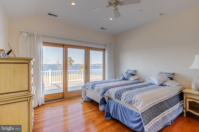 bedroom with a water view, ceiling fan, wood-type flooring, and access to outside