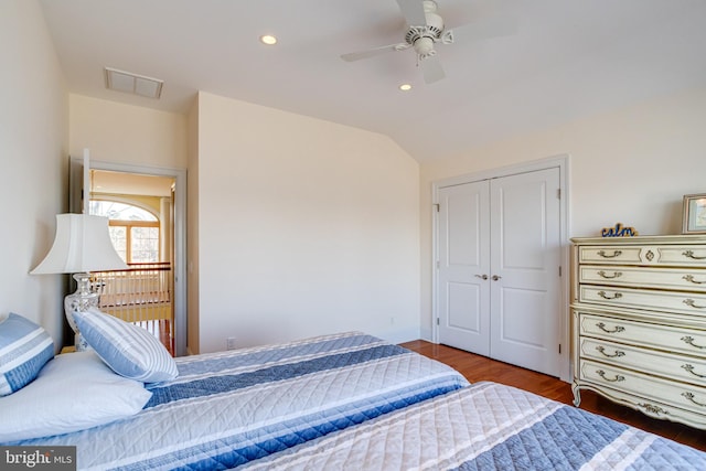 bedroom with dark hardwood / wood-style flooring, vaulted ceiling, a closet, and ceiling fan