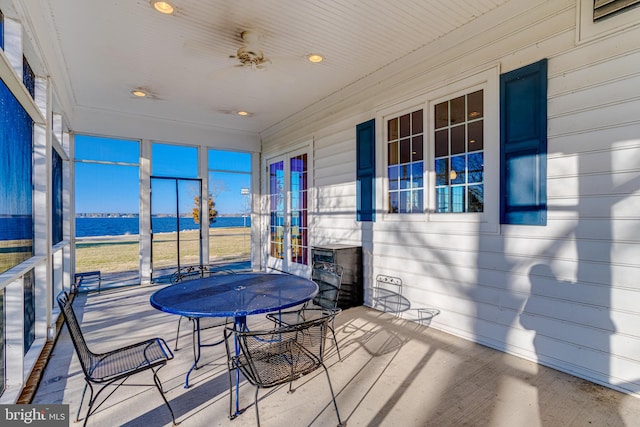 sunroom / solarium featuring ceiling fan and a water view