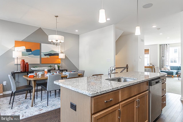 kitchen featuring pendant lighting, a center island with sink, dark wood-type flooring, dishwasher, and sink