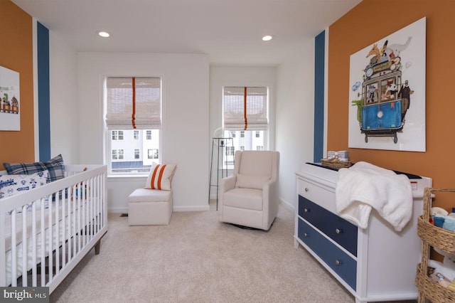 bedroom featuring light carpet and a nursery area