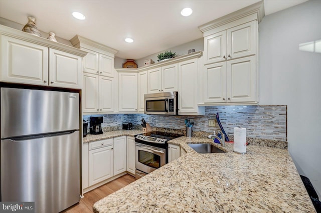 kitchen featuring light stone countertops, light hardwood / wood-style floors, tasteful backsplash, and appliances with stainless steel finishes