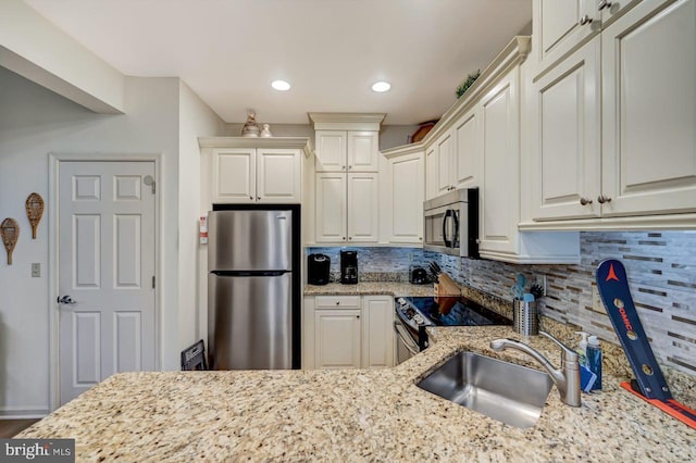 kitchen with stainless steel appliances, light stone counters, tasteful backsplash, and sink