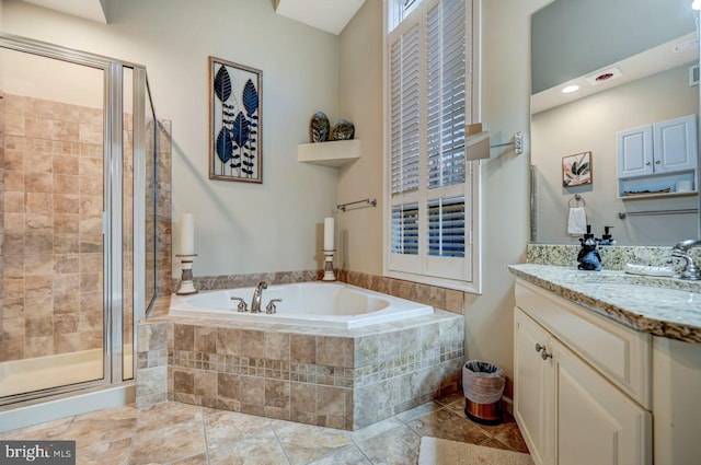 bathroom with tile floors, vanity with extensive cabinet space, and independent shower and bath