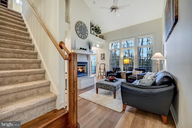 living room with wood-type flooring, a high ceiling, ceiling fan, and a fireplace