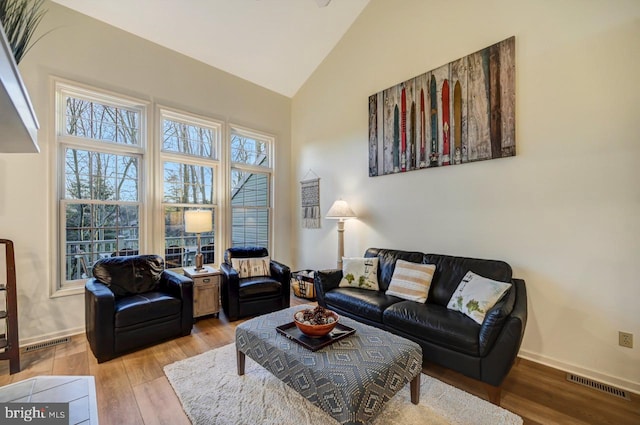 living room with high vaulted ceiling and light wood-type flooring