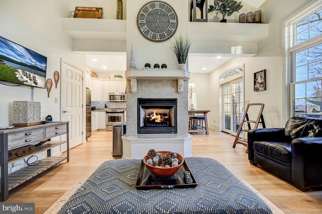 living room featuring light hardwood / wood-style floors, a fireplace, and a high ceiling