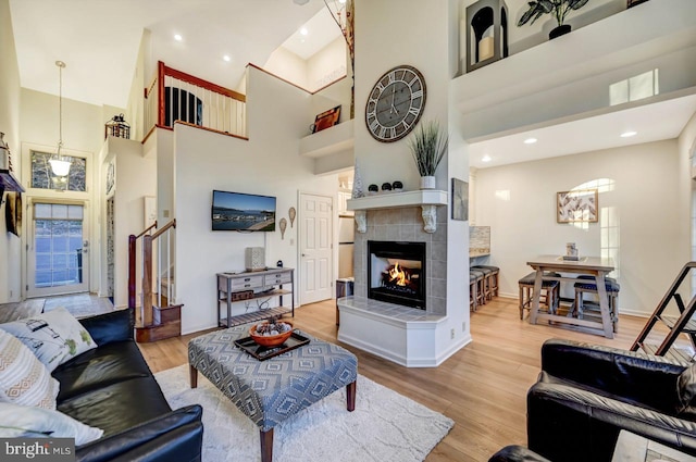 living room featuring hardwood / wood-style floors, a high ceiling, and a tiled fireplace