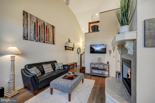 living room featuring high vaulted ceiling, a fireplace, and hardwood / wood-style flooring