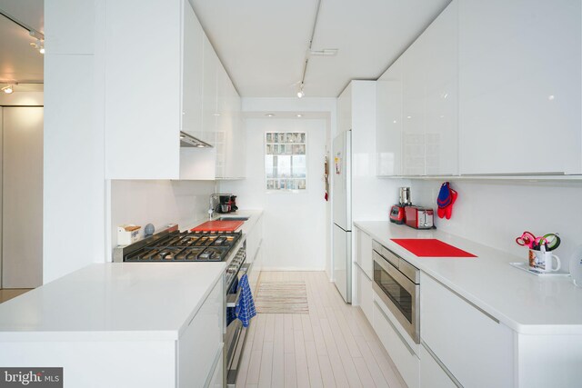 kitchen featuring sink, stainless steel appliances, rail lighting, and white cabinets